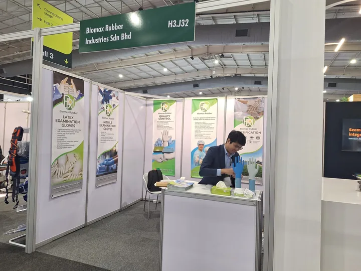 Pacific Resource Global exhibition booth H3.J32 with latex and nitrile glove banners and a staff member at the counter